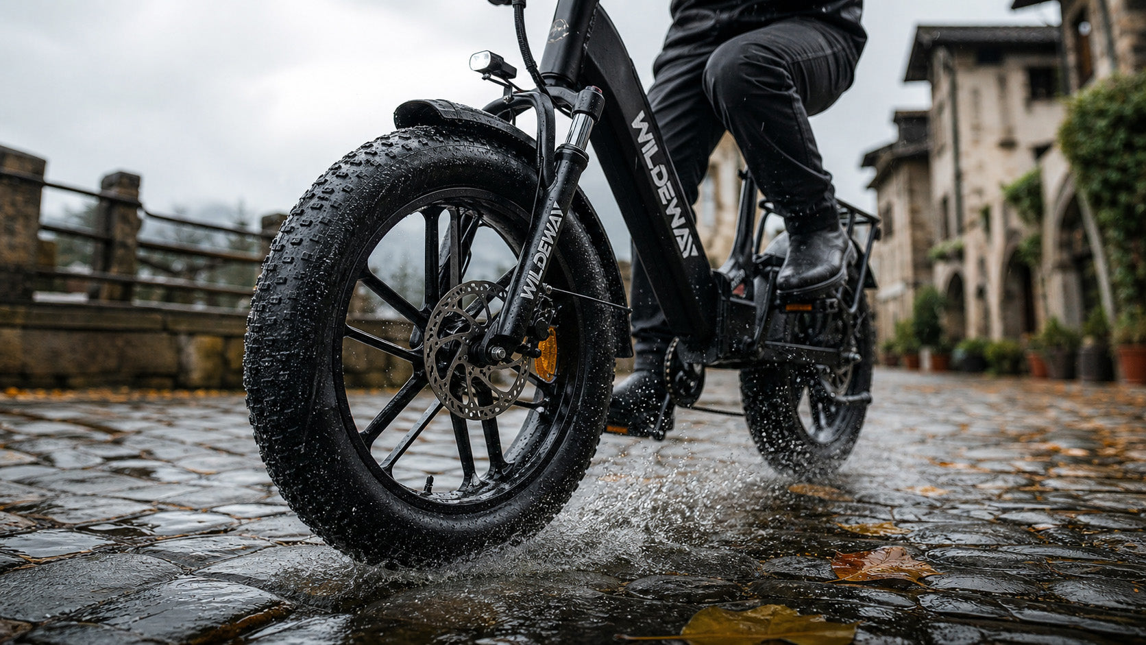 Close-up macro shot of the WILDEWAY Torpedo 20x4.0 fat tire gripping a wet cobblestone street, highlighting the deep tread pattern for maximum safety in the rain.