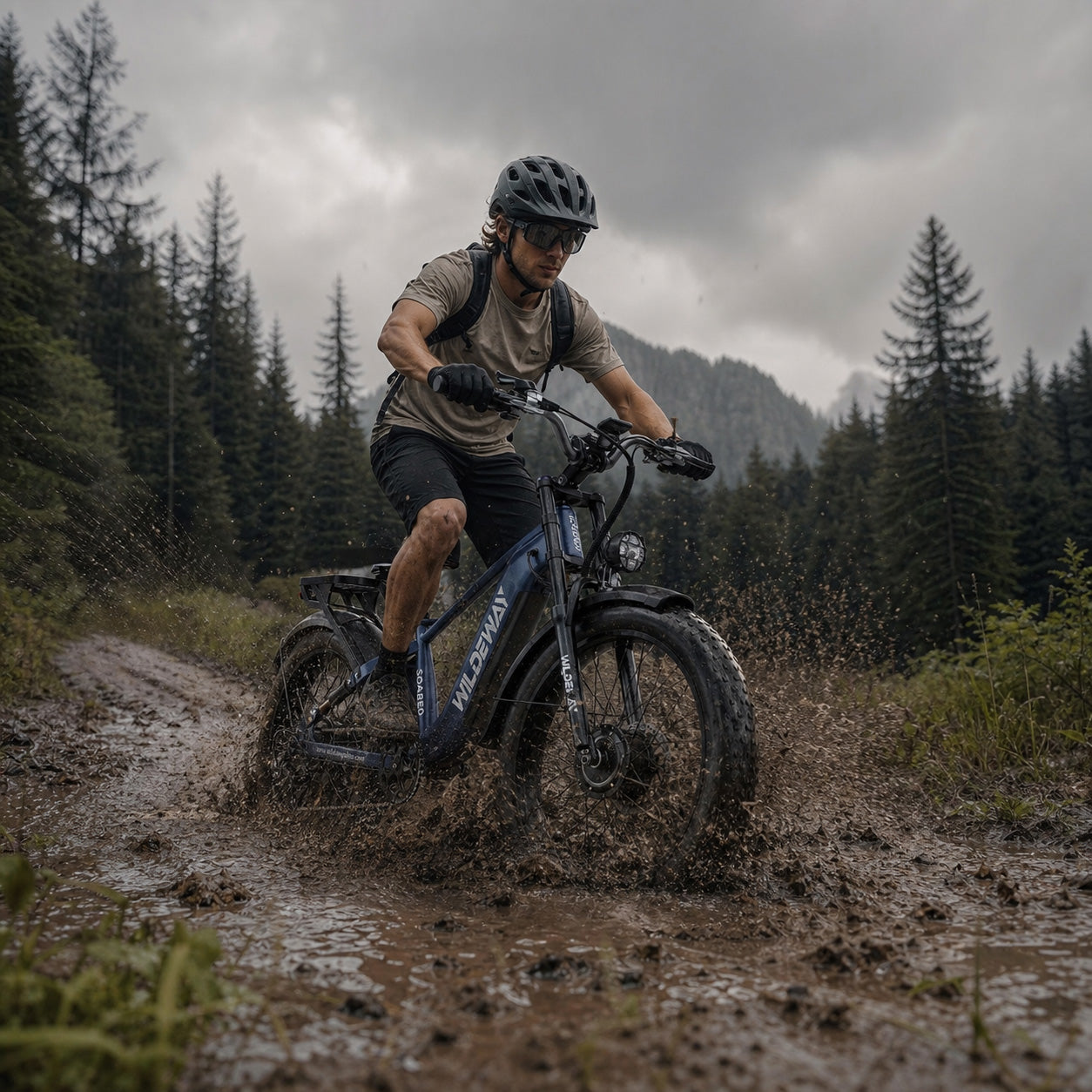 Wildeway Soared Pro Max AWD e-bike splashing through mud on a private woodland trail after a summer rain.