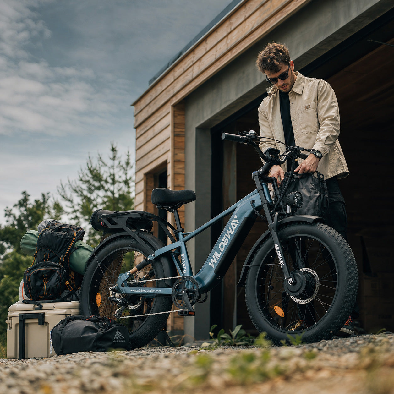 A person preparing their Wildeway Soared e-bike for an epic weekend adventure, showcasing its features like cargo capacity and rugged design.